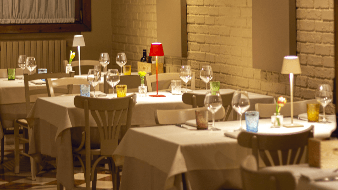 Sala interna elegante di un ristorante a Mirano con tavoli apparecchiati, luce soffusa, mattoni a vista e atmosfera romantica, ideale per cene di coppia.