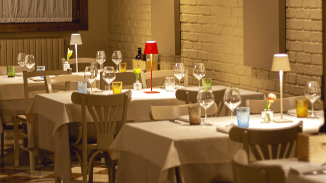 Sala interna elegante di un ristorante a Mirano con tavoli apparecchiati, luce soffusa, mattoni a vista e atmosfera romantica, ideale per cene di coppia.